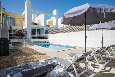 a row of white chairs and an umbrella at Villa Granada in Almancil