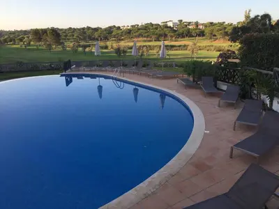 a large swimming pool with chairs and a patio at Quinta Formosa - Villas in Quinta do Lago