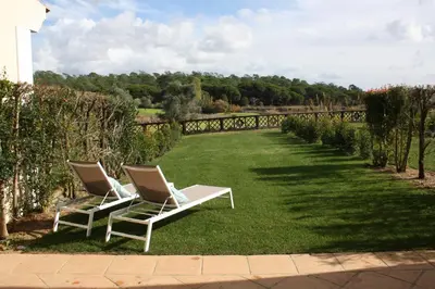 two chairs sitting on the grass in a garden at Quinta Formosa - Villas in Quinta do Lago
