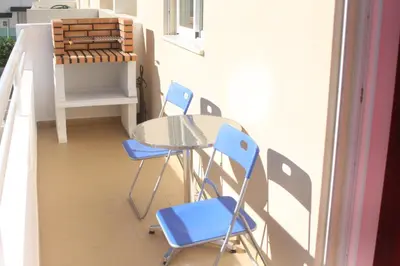 a small balcony with a table and two blue chairs at Albufeira Lovely new Apartment W/ Pool in Albufeira