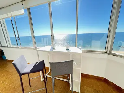 a desk and two chairs in a room with windows at 180° Sea View - Fabulosa vista mar! in Quarteira
