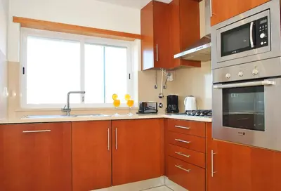 a kitchen with wooden cabinets and a sink and a window at Townhouse Mar 1 by Algarve Vacation in Albufeira