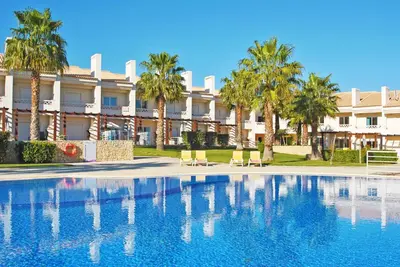 a swimming pool in front of a building with palm trees at Townhouse Mar 1 by Algarve Vacation in Albufeira