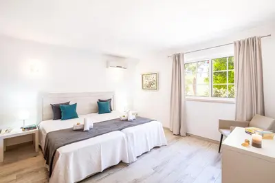 a white bedroom with a large bed with blue pillows at Villa Valentina by Algarve Vacation in Almancil