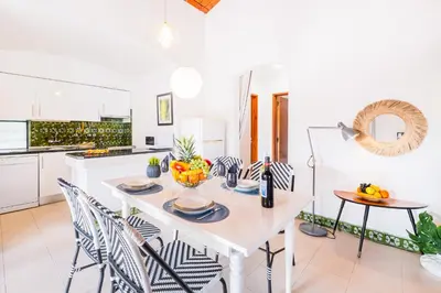 a white kitchen with a white table and chairs at Villa Belize by Algarve Vacation in Albufeira