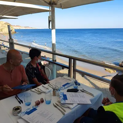 a group of people sitting at a table near the beach at Olhos do Mar in Albufeira