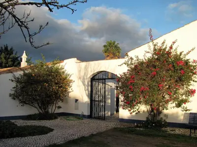 a white building with a gate and two trees at Quinta Quinze in Boliqueime