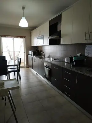 a kitchen with white cabinets and a table and chairs at Edifice Ibérico in Albufeira