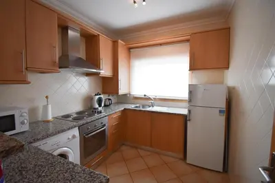 a kitchen with wooden cabinets and a white refrigerator at Old Village Prestige 101 in Vilamoura