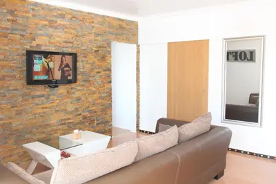 a living room with a couch and a tv on a brick wall at Beach Center 2 - 300m beach in Albufeira