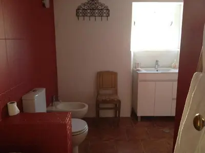 a bathroom with a toilet and a sink and a chair at Casa da Esperança – Rural and beach Villa in Algarve in Boliqueime