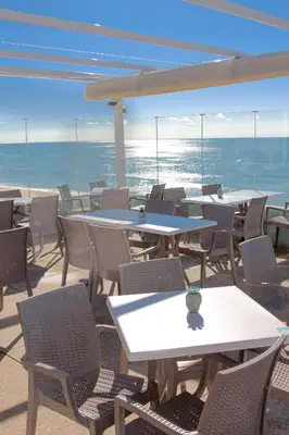a white building with a fence and palm trees at Golden Beach Guest House & Rooftop Bar in Faro