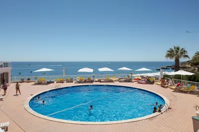 a swimming pool next to the ocean with people in it at Pé na Praia in Albufeira