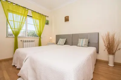a bedroom with a red wall and a bed with white pillows at Quinta das Yuccas in Boliqueime