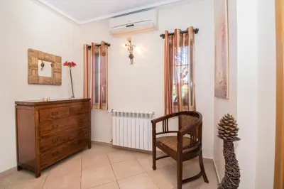 a living room with a wooden dresser and a chair at Quinta das Yuccas in Boliqueime