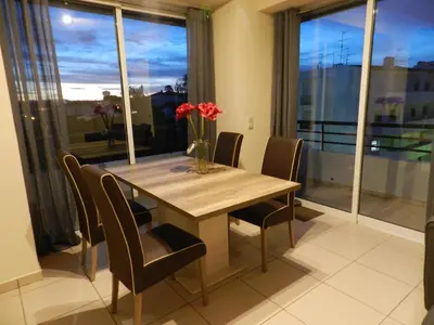 a dining room table with chairs and a vase of flowers at Casa Sensa in Albufeira