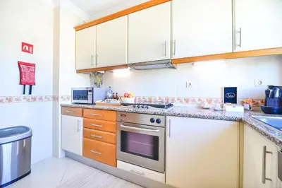 a kitchen with white cabinets and a stove top oven at L14 by MTPhomes in Vale de Pedras