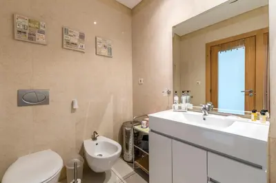 a bathroom with a toilet and a sink and a mirror at Beachfront flat, private parking, pools, sea at less than 200 m in Albufeira
