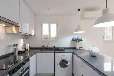 a white kitchen with a washing machine in it at Boat View - Marina Plaza - By VilamouraSun in Vilamoura