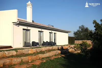 a white house with chairs on a wall at Mercedes Country House in Faro