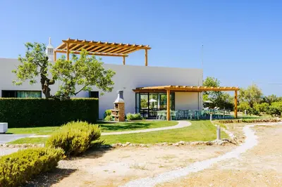 a white house with a wooden pergola at Mercedes Country House in Faro