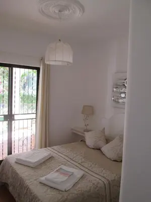 a white bedroom with a bed and a window at Casa Vila Verde in Quarteira
