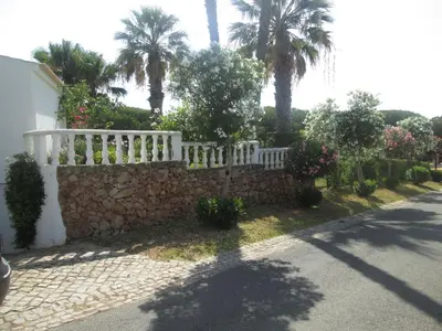 a white fence on a stone wall next to a street at Casa Vila Verde in Quarteira