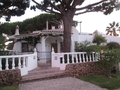 a white house with a white fence and a tree at Casa Vila Verde in Quarteira