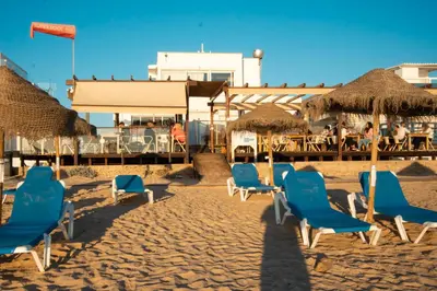 a group of chairs and umbrellas on a beach at Wax Suite Life is a beach in Faro