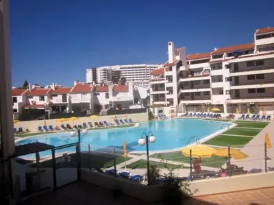 a large swimming pool with chairs and umbrellas and buildings at Aqua Magna Apartment in Albufeira