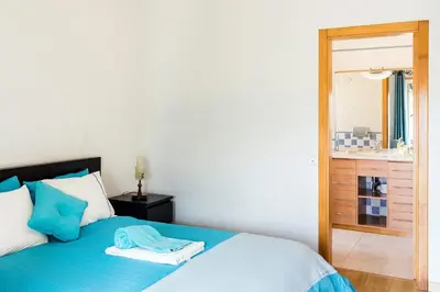 a bedroom with a blue bed and a chandelier at Laguna Formosa in Faro