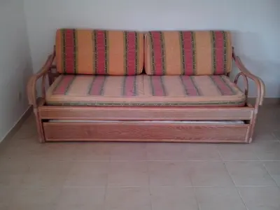 a wooden couch sitting in a corner of a room at Apartment with 1 Bedroom L in Albufeira