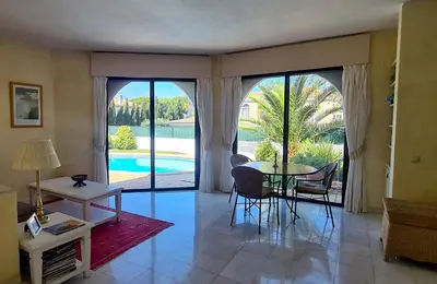 a living room with a table and a view of a pool at Dunas Douradas Beach Villa in Benfarras
