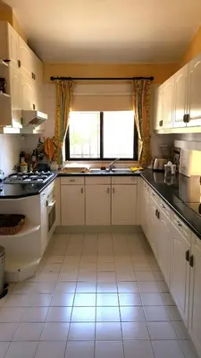 a kitchen with white cabinets and a sink and a window at Dunas Douradas Beach Villa in Benfarras