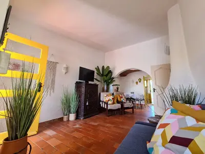 a living room with a yellow door and some plants at Aldeia do Golf - Vila I8 in Vilamoura