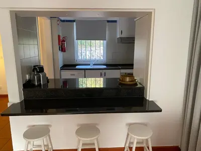 a kitchen with a counter with three stools in it at Quinta do lago & golf in Quinta do Lago
