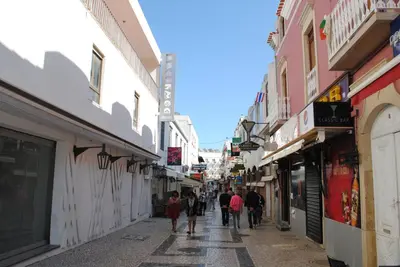 a group of people walking down a street with buildings at Garden Hill Apartment in Albufeira