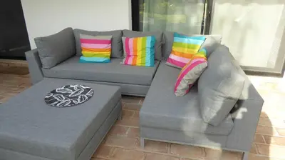 a gray couch with colorful pillows and a table at By the Beach in Almancil