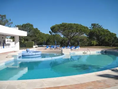 a large swimming pool with blue chairs in it at By the Beach in Almancil