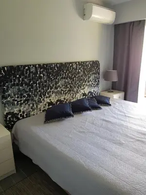 a bedroom with a large white bed with blue pillows at By the Beach in Almancil