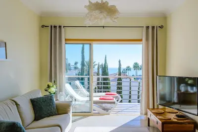 a living room with a couch and a sliding glass door at BnB Homes Ocean view Apartment with Lovely Terrace, 2 Swimming pools & Tennis court in Albufeira