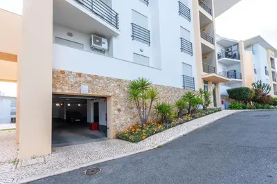 a swimming pool with chairs and umbrellas next to a house at BnB Homes Ocean view Apartment with Lovely Terrace, 2 Swimming pools & Tennis court in Albufeira