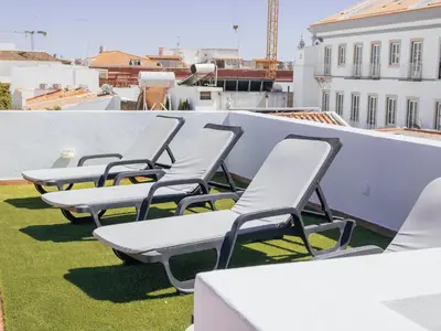 a row of chaise lounge chairs on a roof at Dear Faro - Guest House in Faro