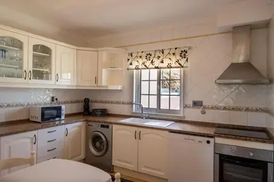 a kitchen with white cabinets and a washer and dryer at Casa Galé - Joia das Sesmarias 600mts praia in Albufeira