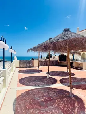 a patio with an umbrella and the beach at Albufeira Jardim 2 Studio in Albufeira
