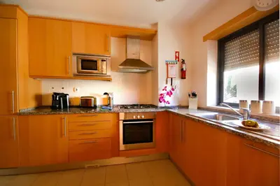 a kitchen with wooden cabinets and a sink and a microwave at Apartamento Corcovada - By Bedzy in Albufeira