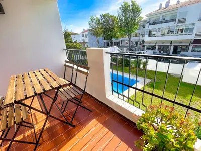 a balcony with a wooden bench and a swimming pool at Urbisol 202-Albufeira in Albufeira