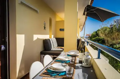 a table and chairs on a balcony with an umbrella at Olhos Do Mar Albufeira in Albufeira