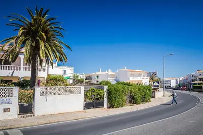 a person walking down a street with a palm tree at Olhos Do Mar Albufeira in Albufeira