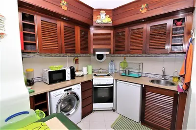 a kitchen with wooden cabinets and a washer and dryer at Belavista Centre - Albufeira in Albufeira